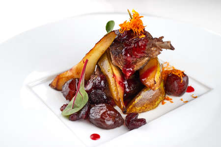 Duck leg with pear on a white plateの写真素材