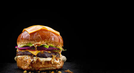 Burger with meat cheese and vegetables on a black backgroundの写真素材