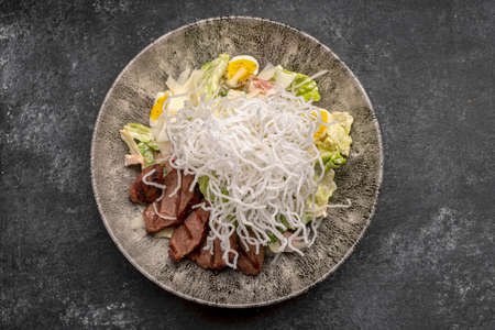 Salad with veal, tomatoes, eggs on a plateの写真素材
