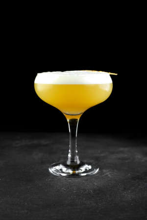 bourbon with lemon juice, sugar syrup and egg white in glass on black. Vertical orientation.