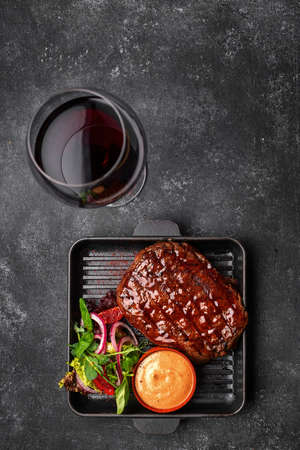 Grilled pork steak with sauce and vegetables in a skillet with place for textの写真素材