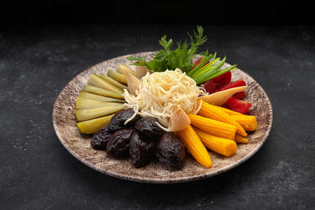 Pickled vegetables on a dark background cucumbers tomatoes herbs