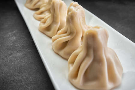 Cooked Khinkali on a white plate on a dark background