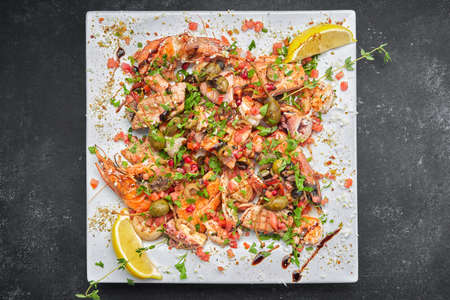 Seafood cocktail scallop, shrimp, fish, squid, with capers and herbs on a plateの写真素材