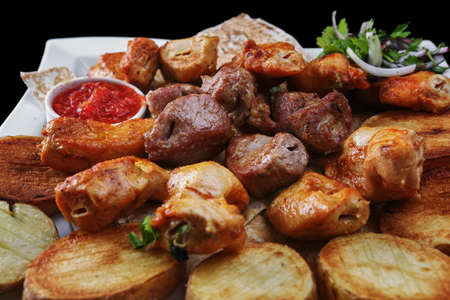 Assorted meat with baked potatoes, on a white plate
