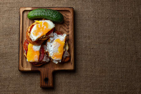 Homemade sandwiches with meat, potatoes, tomato, cucumber and fried egg on a wooden boardの写真素材