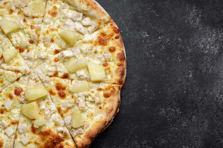 Pizza with cheese, pineapple and chicken on a dark backgroundの写真素材