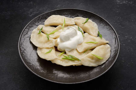 Boiled Ukrainian dumplings on a dark background, with space for text