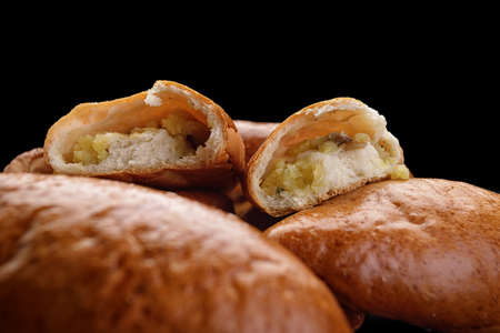 Several baked pies with potatoes on a dark background