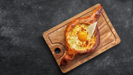 Adjarian khachapuri On a wooden board, on a dark backgroundの写真素材