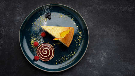 Cheesecake with orange chips and raspberries, on a plate, on a dark backgroundの写真素材