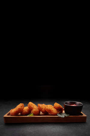 Meat nuggets with ketchup on a dark background, on a wooden surfaceの写真素材
