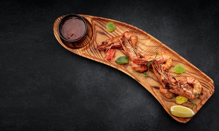 Fried grilled shrimp with garlic sauce, on a wooden board, on a dark backgroundの写真素材
