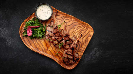 Rack of lamb with sauce and herbs, on a wooden boardの写真素材