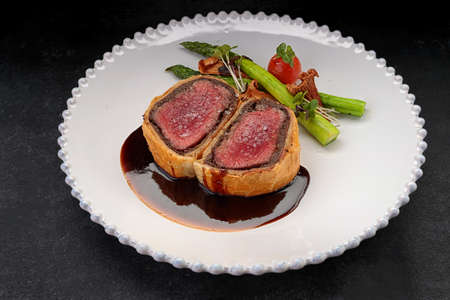 Beef Wellington with chanterelles, asparagus and black truffle with spicy Razmarin sauce, on a black backgroundの写真素材