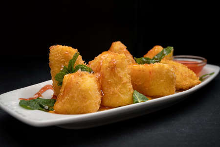 Nuggets with cheese. mint and jam, on a plate, on a dark background