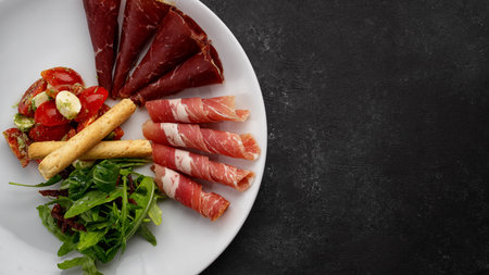 Meat appetizer with vegetable salad, arugula and grissini