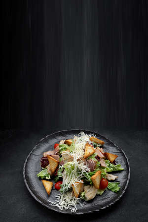 Caesar salad on a black plate. Verticalの写真素材