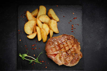 Meat steak on black slate with fried potatoes. argentinianの写真素材