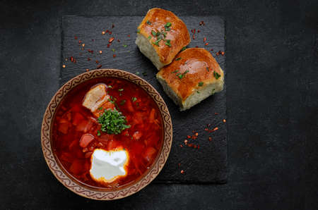 Red borscht with buns with garlic and sour cream, on a dark backgroundの写真素材