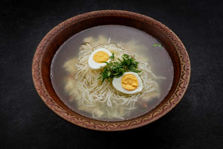 Chicken broth, with vermicelli, herbs and egg, on a dark backgroundの写真素材