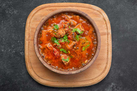 Georgian national dish Ojakhuri, in a clay plate, on a wooden board, on a dark backgroundの写真素材