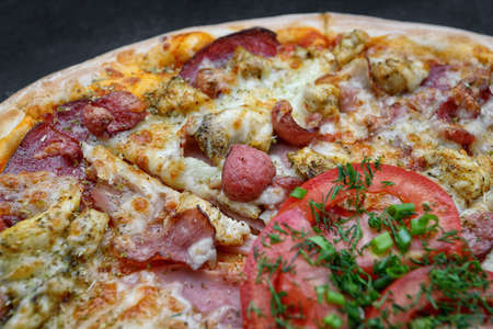 Pizza with sausage meat and chicken, cheese and tomatoes on a gray concrete background, with selective focus. Horizontalの写真素材