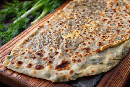 Azerbaijani kutab with herbs on a wooden board. selective focus