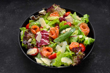 Salad with salmon, parmesan cheese, tomatoes and salad mix on a plateの写真素材
