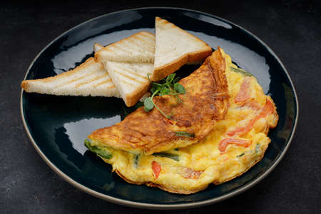 Omelet with vegetables and toast on a plateの写真素材