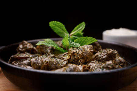 Dolma with sour cream and mint on a plate. Selective focus