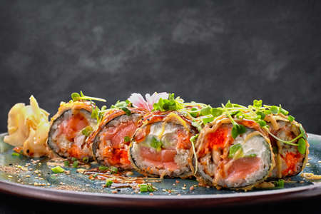 Warm roll with salmon, tiger prawn, eel, avocado, on a plate, on gray concreteの写真素材