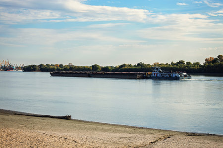 Cargo barge sails to the port along the shore. Blue skyの写真素材