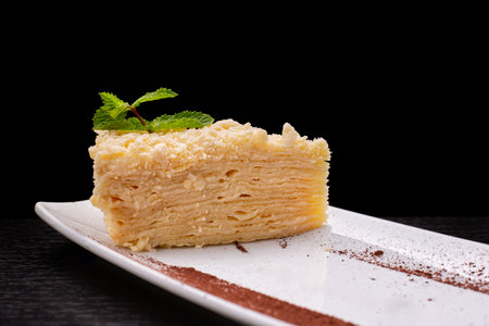 Piece of Napoleon cake with mint on a plate. on a dark backgroundの写真素材