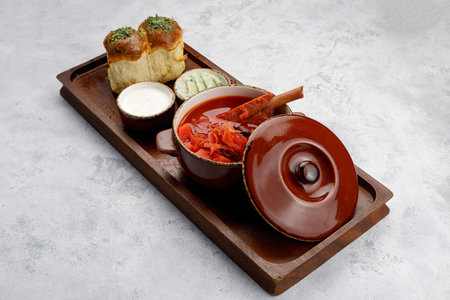 Ukrainian borscht with sour cream and donuts with garlic, on a wooden board, On a light background