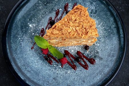 A piece of Napoleon cake with berries and mint, on a black backgroundの写真素材