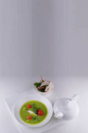 Cream of green pea soup with tomatoes and croutons, on a white backgroundの写真素材