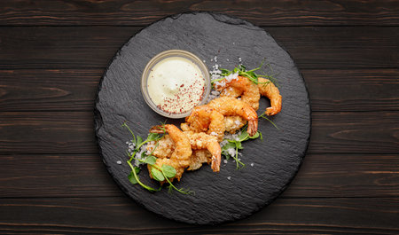 Fried shrimp in batter with sauce, on black slate