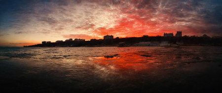 Panorama of the city from the pier on the sea, against the background of the sunset. Illustrationの写真素材
