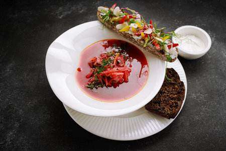 Ukrainian borscht with bruschetta with vegetables, on a plate, on gray concrete