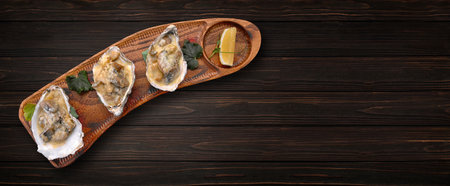 Rapana clams baked with cheese on a wooden board, on a wooden background. Banner