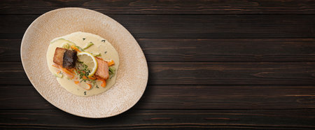 Grilled salmon steak with vegetables, sauce and lemon, on a wooden background. Bannerの写真素材