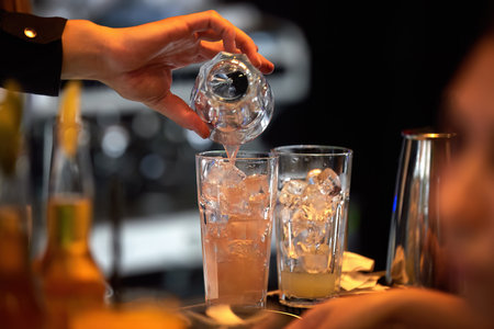 The bartender pours cocktails at the bar counter. Blurred background, bokeh