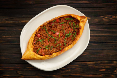 Mouth-watering pide stuffed with seasoned meat on wooden background