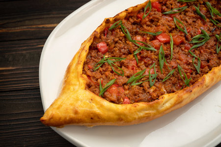 Mouth-watering pide stuffed with seasoned meat on wooden background