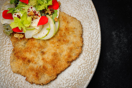 fried beefsteak on a plate with salad, on a dark backgroundの写真素材