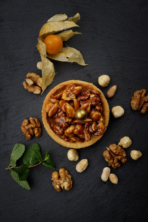 Dessert basket with nuts and caramel, on a black stone with mint