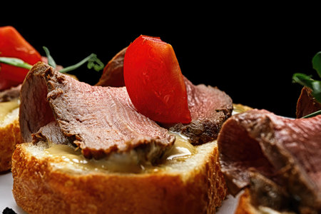 Bruschetta with meat, sauce and tomatoes, on a dark backgroundの写真素材