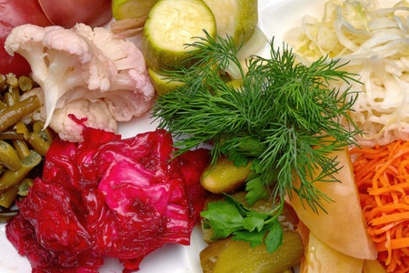 Pickled vegetables with dill on a plate, on dark concrete. close up