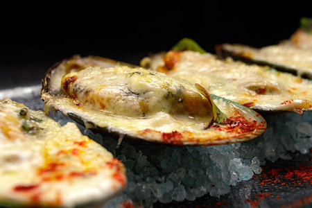 New Zealand mussels baked with cheese and spices, on a dark backgroundの写真素材